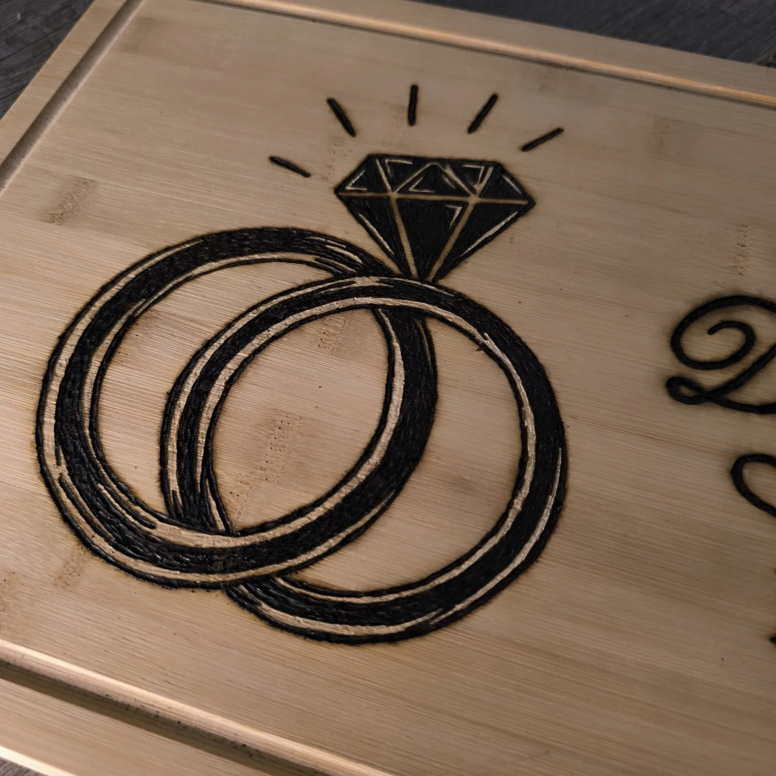 Detailansicht der eingebrannten Ringe und des Diamanten auf dem Bambusbrettchen zur Diamantenhochzeit.