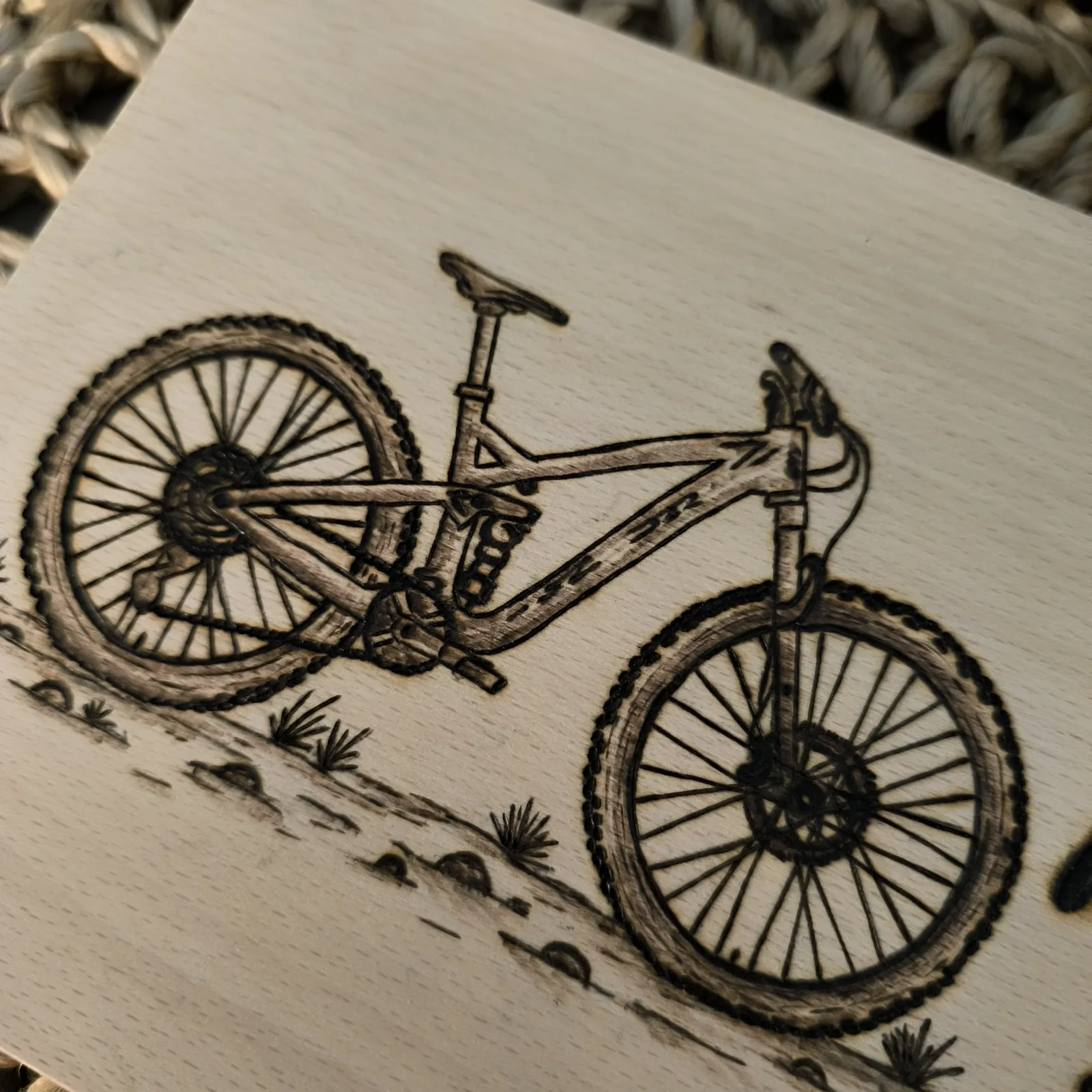 Detailansicht des eingebrannten Mountainbikes auf einem Buchenholzbrettchen.