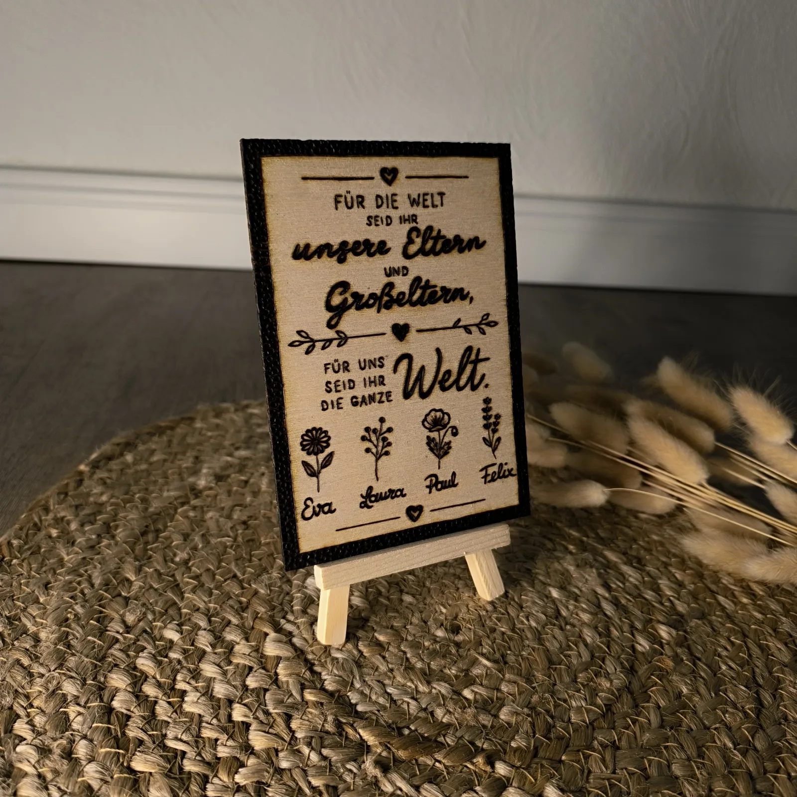 Detailansicht des Holzschilds mit Spruch für Eltern und Großeltern, Blumen und vier Namen.