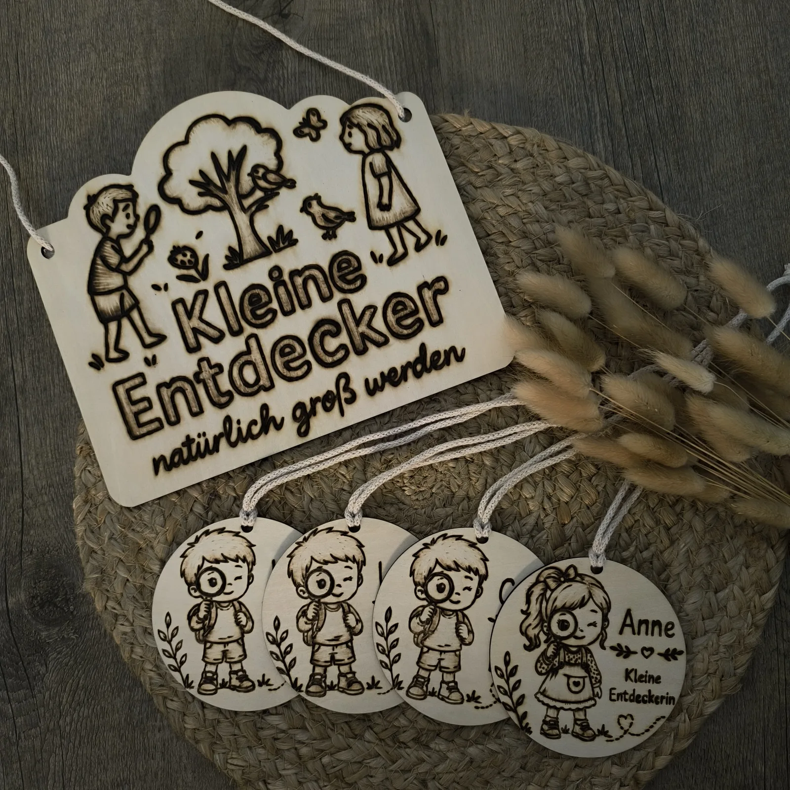 Holzschild Kleine Entdecker mit vier runden personalisierten Holzanhängern für Kinder.
