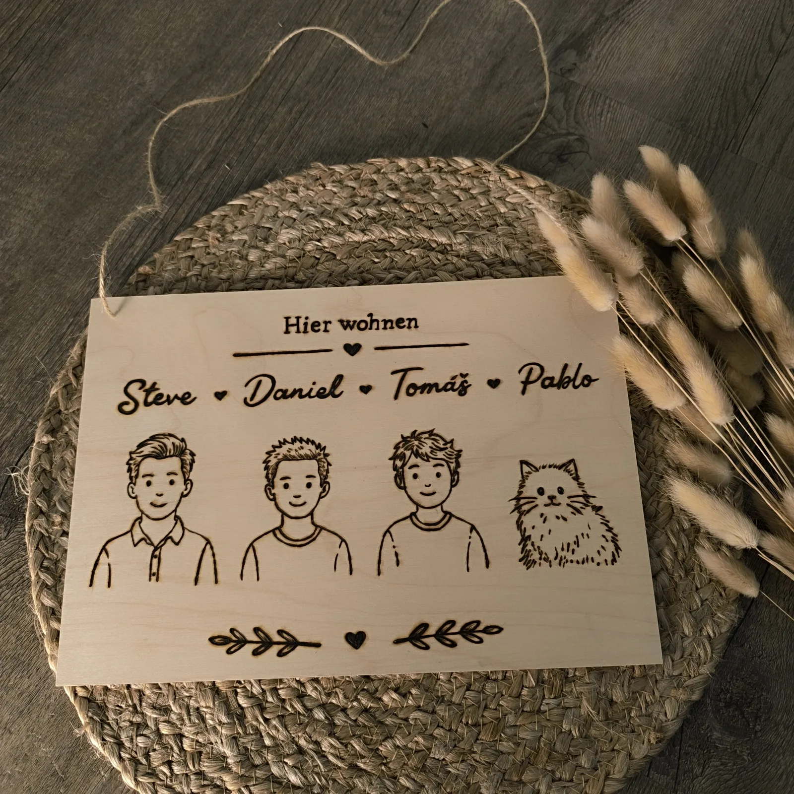 Holzschild zum Aufhängen mit drei Personen, Katze und den Namen Steve, Daniel, Tomáš und Pablo.