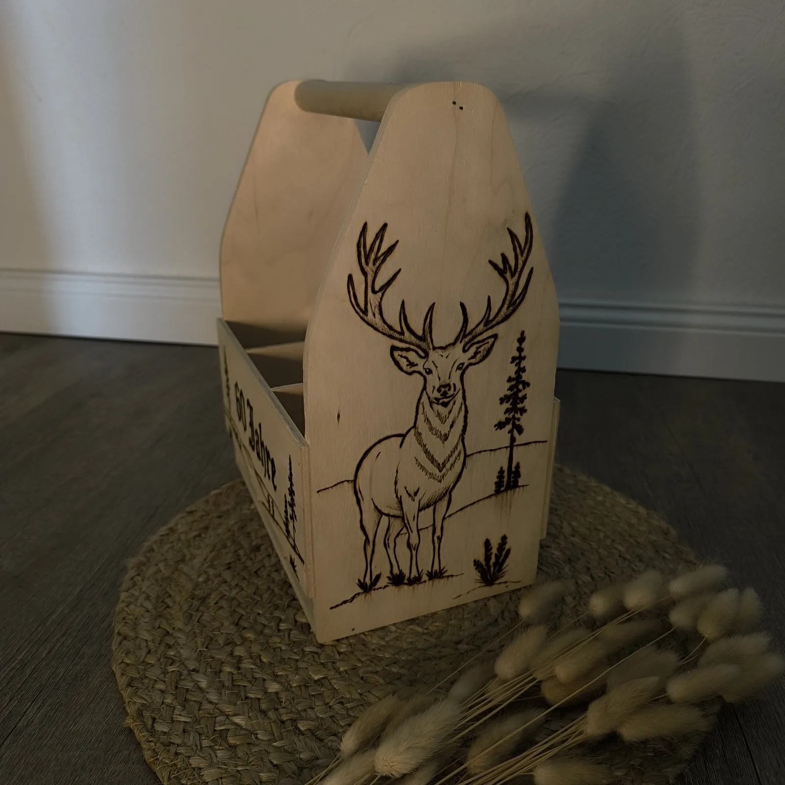 Holzträger mit detailreichem Hirschmotiv und Bäumen auf der Seitenfläche.