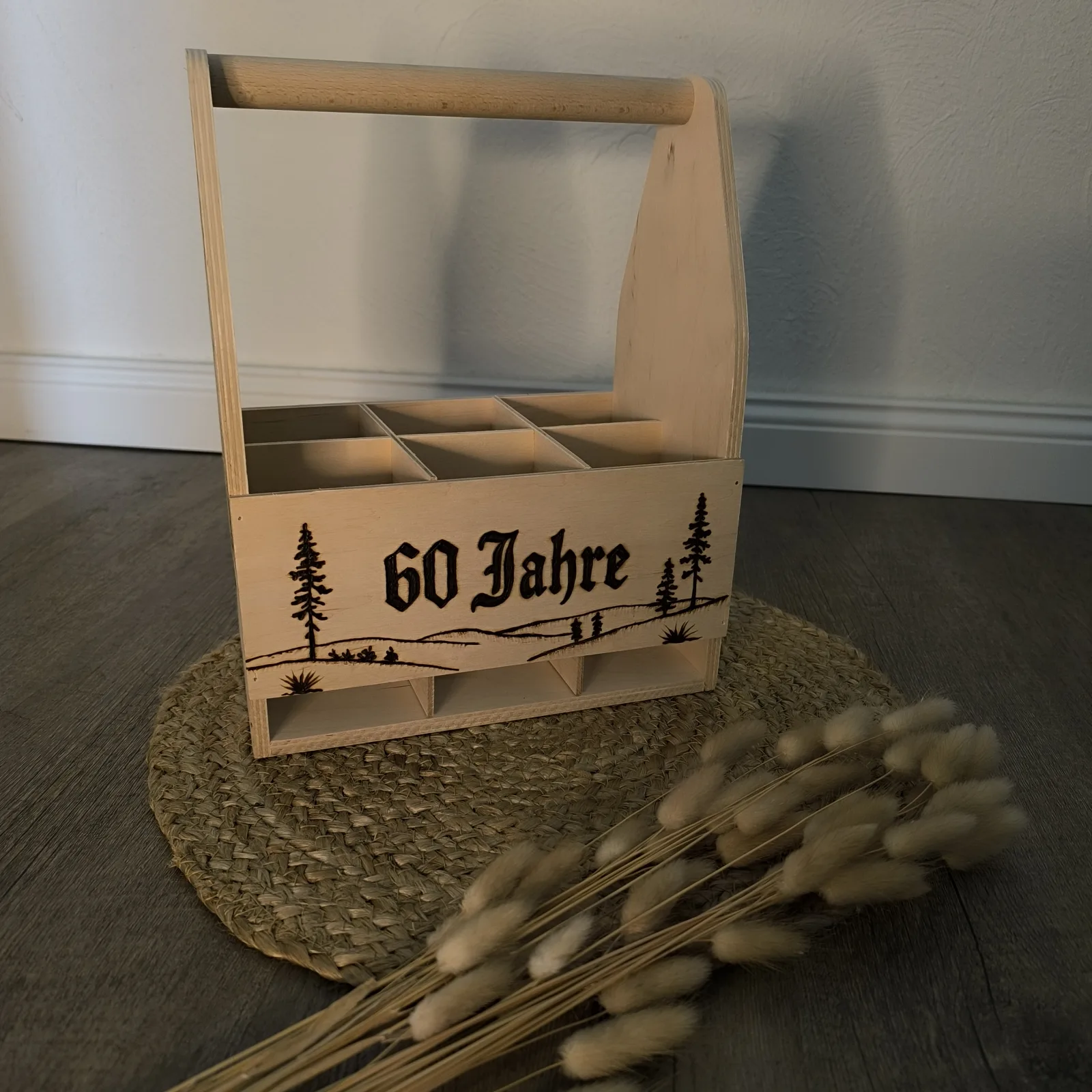 Holzträger mit mehreren Fächern, Waldmotiv und der eingebrannten Aufschrift 60 Jahre.