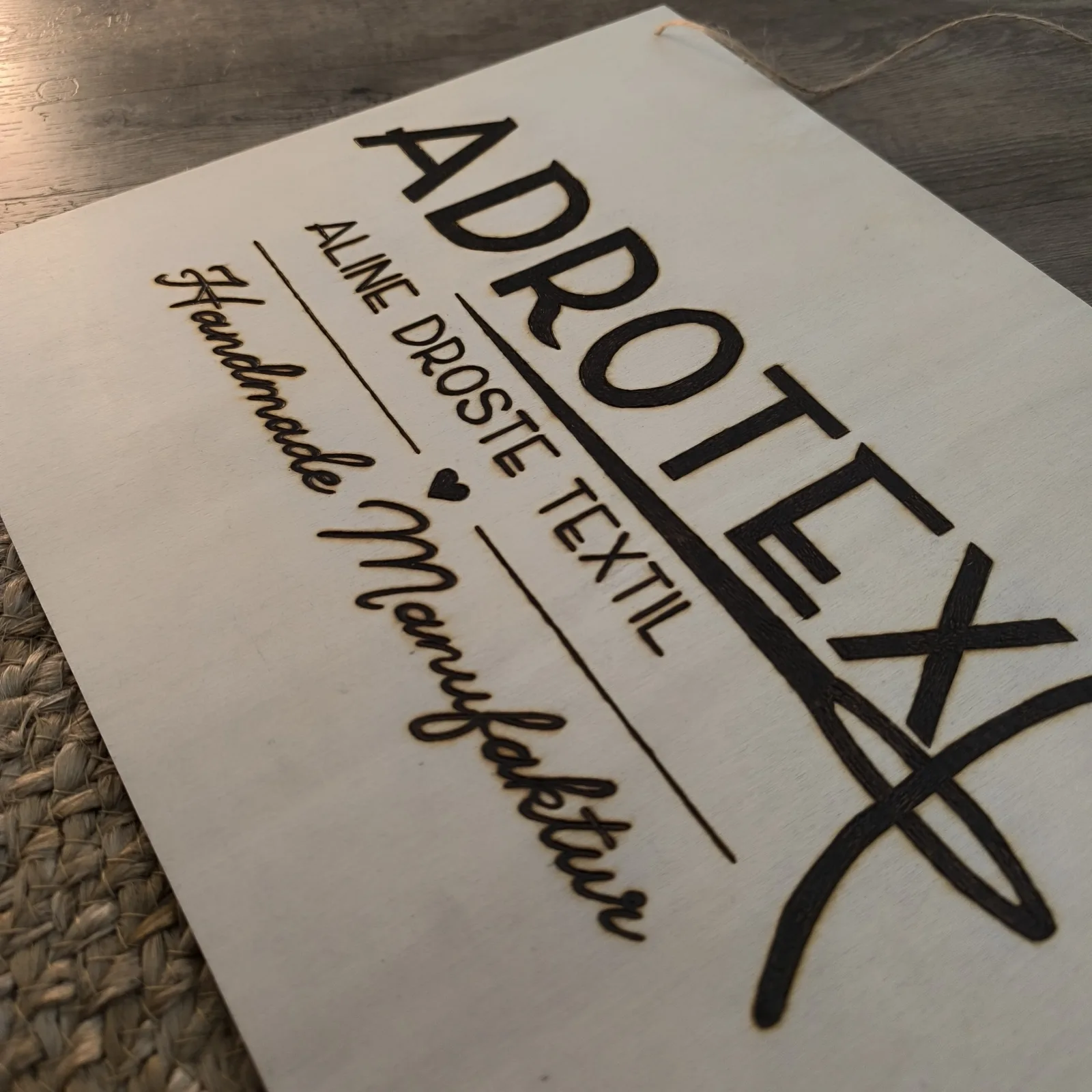 Nahaufnahme eines gravierten Holzschilds mit ADROTEX Logo und Handmade Manufaktur.