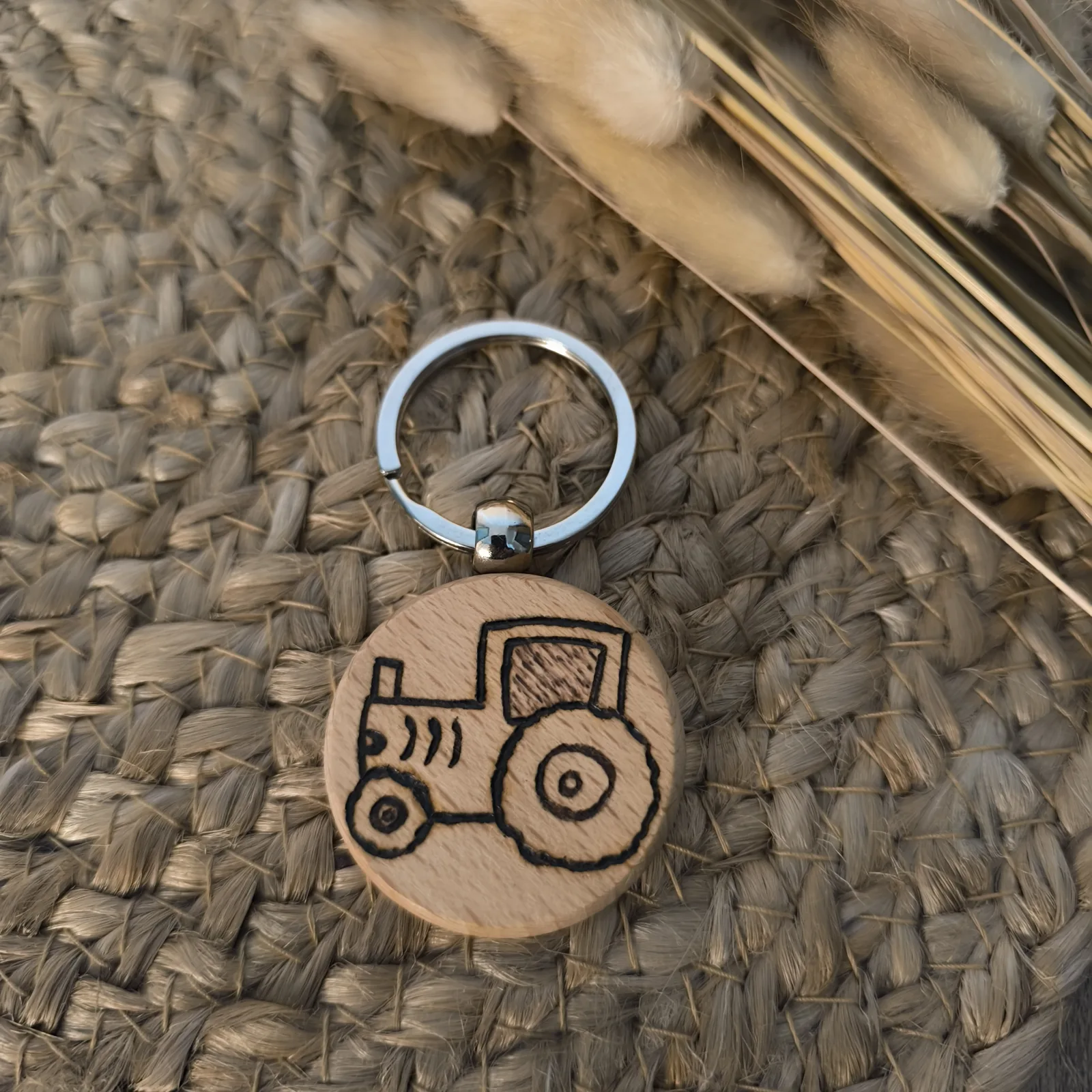 Nahaufnahme eines runden Holz Schlüsselanhängers mit eingebranntem Traktor Motiv.
