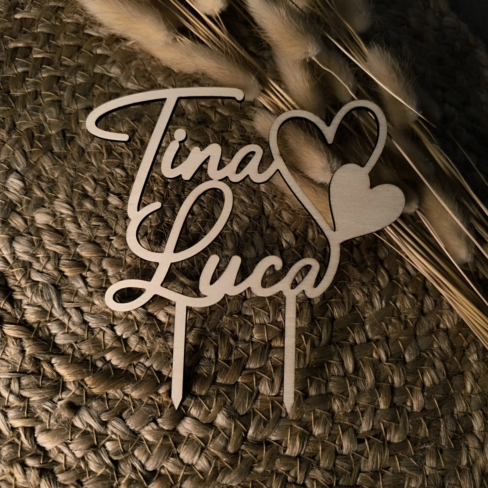 Personalisierter Caketopper aus Holz mit den Namen Tina und Luca sowie zwei Herzen.