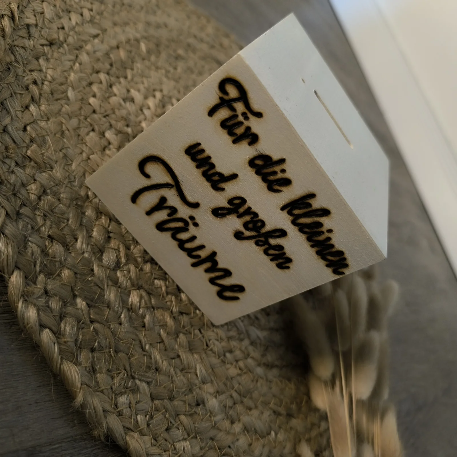 Weiße Holzspardose mit Aufschrift Für die kleinen und großen Träume auf Jutematte.