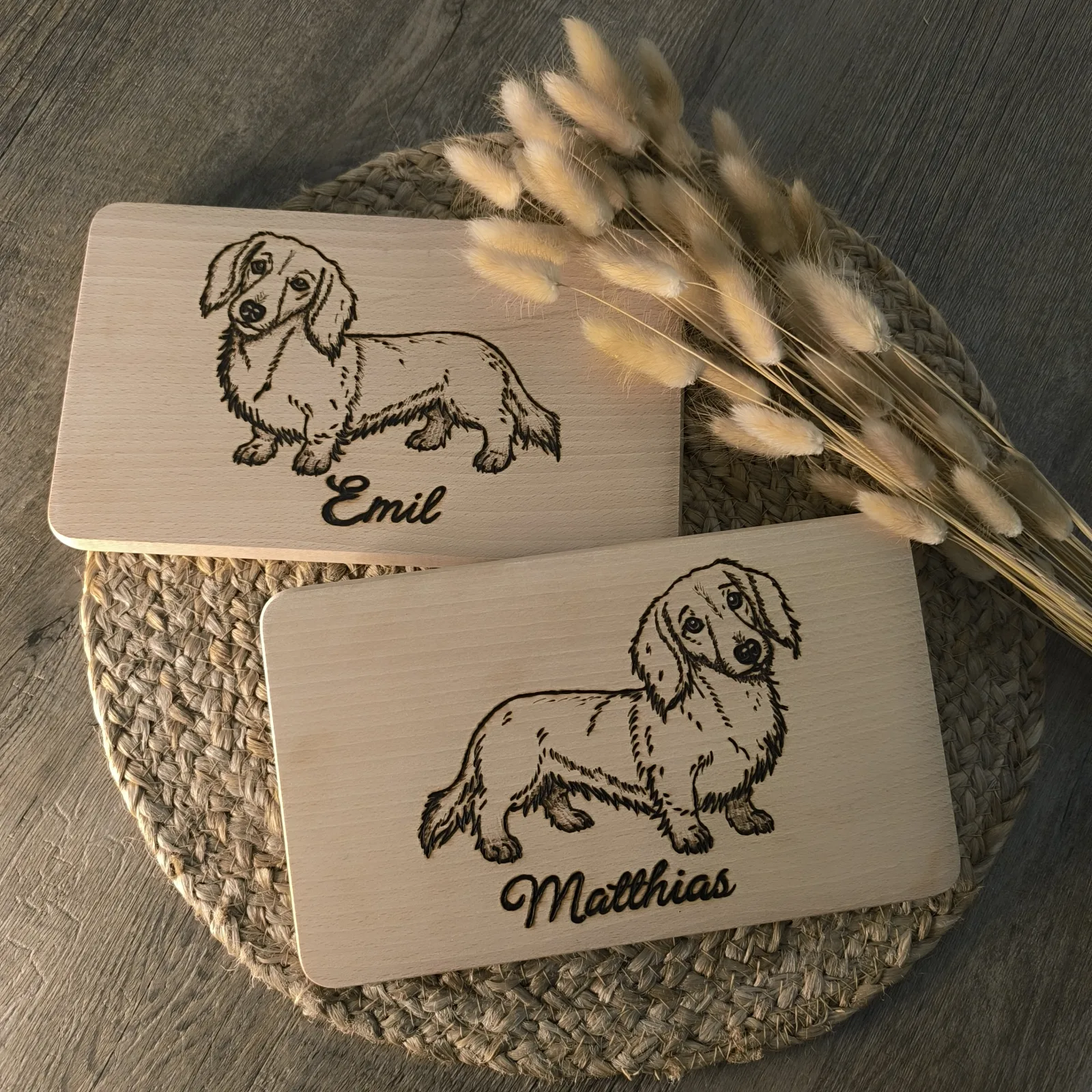 Zwei Buchenholzbrettchen mit Dackelmotiven und den eingebrannten Namen Emil und Matthias.
